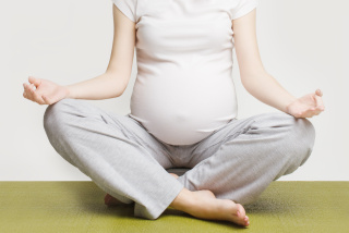 Closeup of pregnant woman sitting in lotus pose